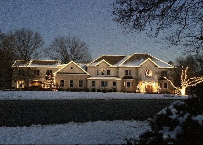 Large estate home with roofline lighting and snow